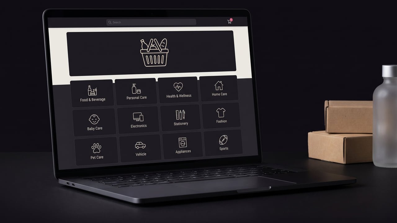 A laptop showing the dark-mode staff storefront: a search bar, a promo banner and a twelve-tile category grid, with plain kraft delivery boxes stacked beside it.