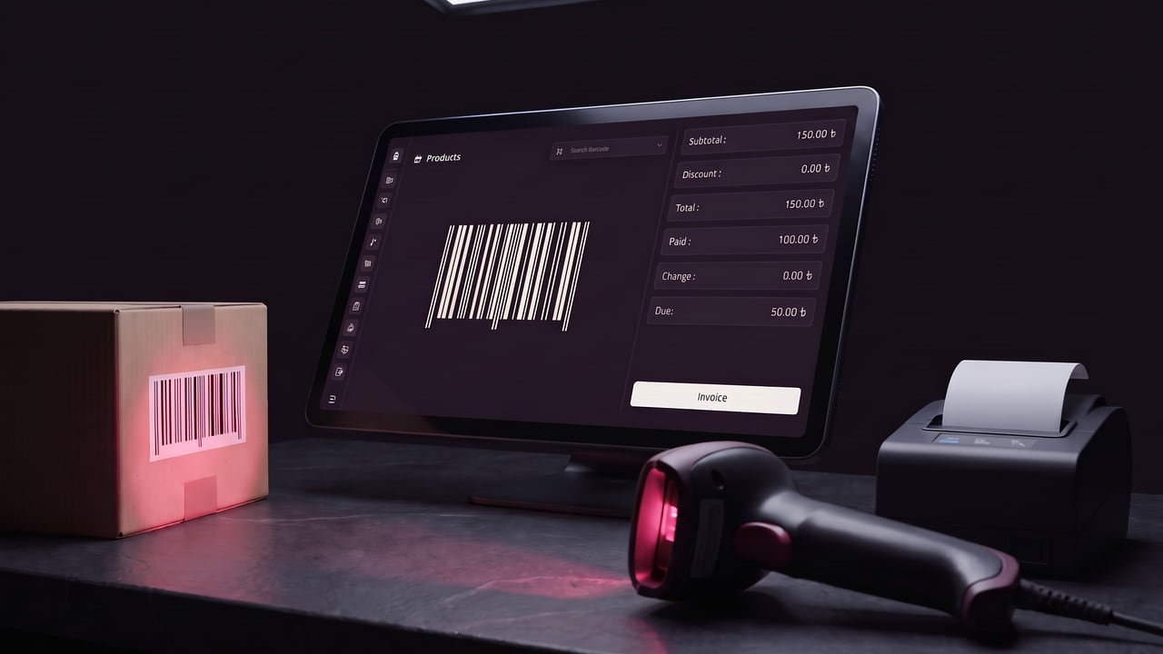A checkout counter: a point-of-sale terminal showing a scanned item and its running totals, a receipt printer, and a handheld scanner reading the barcode on a parcel.